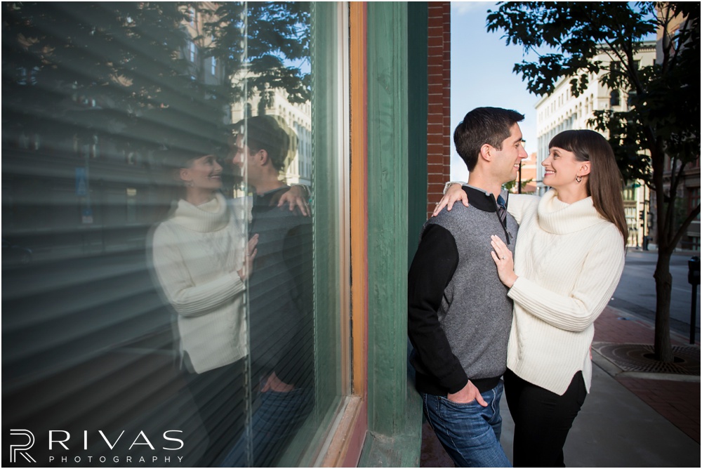 Timeless Garment District Engagement Session | A photo of an engaged couple in fall sweaters hugging on a street in downtown Kansas City. 