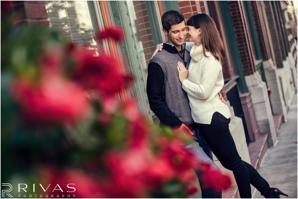Timeless Garment District Engagement Session | A photo of an engaged couple in fall sweaters hugging on a street in downtown Kansas City. 