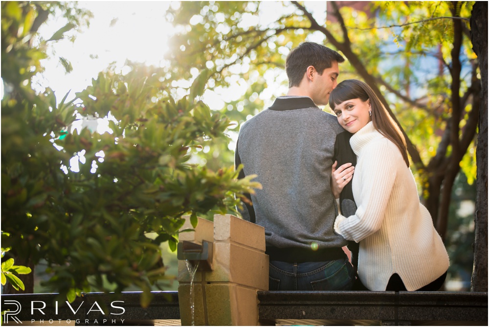 Timeless Garment District Engagement Session | A picture of an engaged couple in fall sweaters sitting on a bench in downtown Kansas City. 