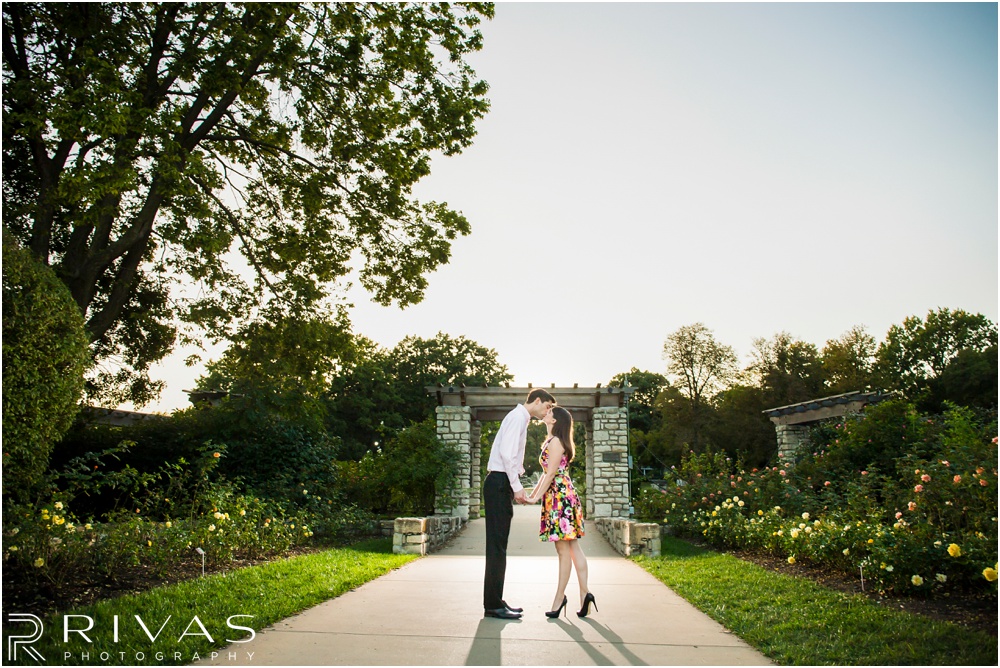 Timeless Garment District Engagement Session | A picture of an engaged couple kissing outside the rose garden at Loose Park. 