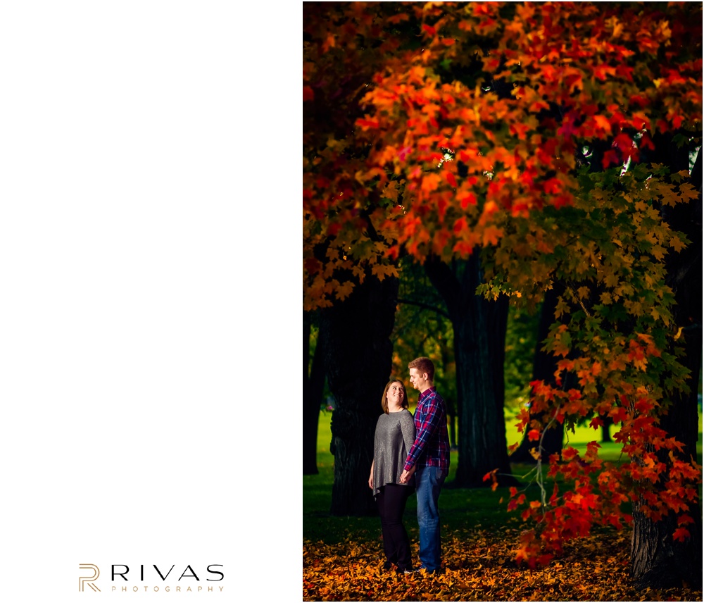 Colorful Fall Engagement Session | An image of an engaged couple embracing underneath a tree covered in orange leaves at Loose Park. 