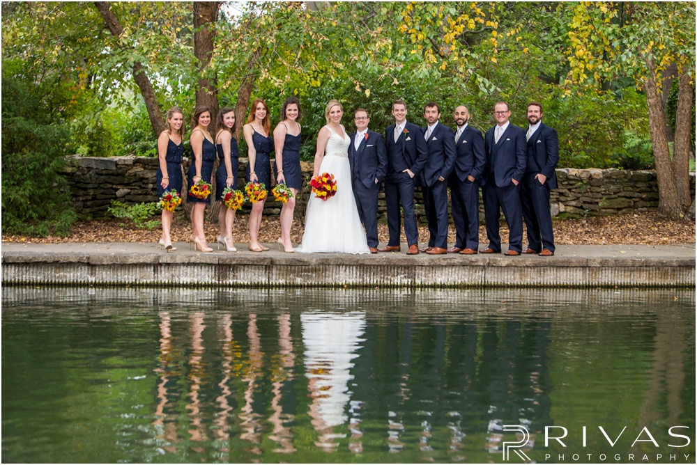 Rustic Outdoor Fall Wedding | A picture of a bride and groom with their wedding party by the pond at Loose Park. 