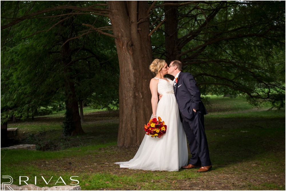 Rustic Outdoor Fall Wedding | An image of a bride and groom on their wedding day underneath a pine tree at Loose Park