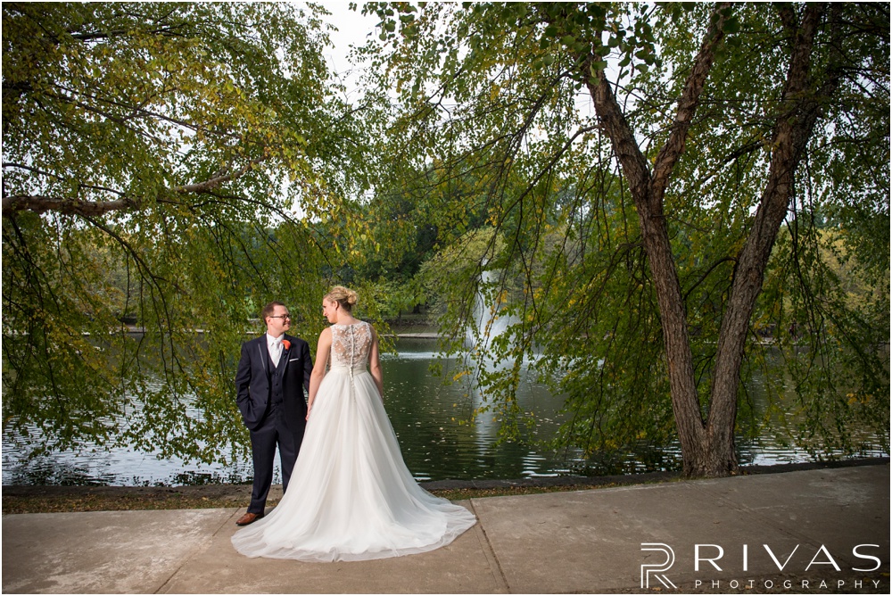 Rustic Outdoor Fall Wedding | An image of a bride and groom holding hands on their wedding day by the pond at Loose Park