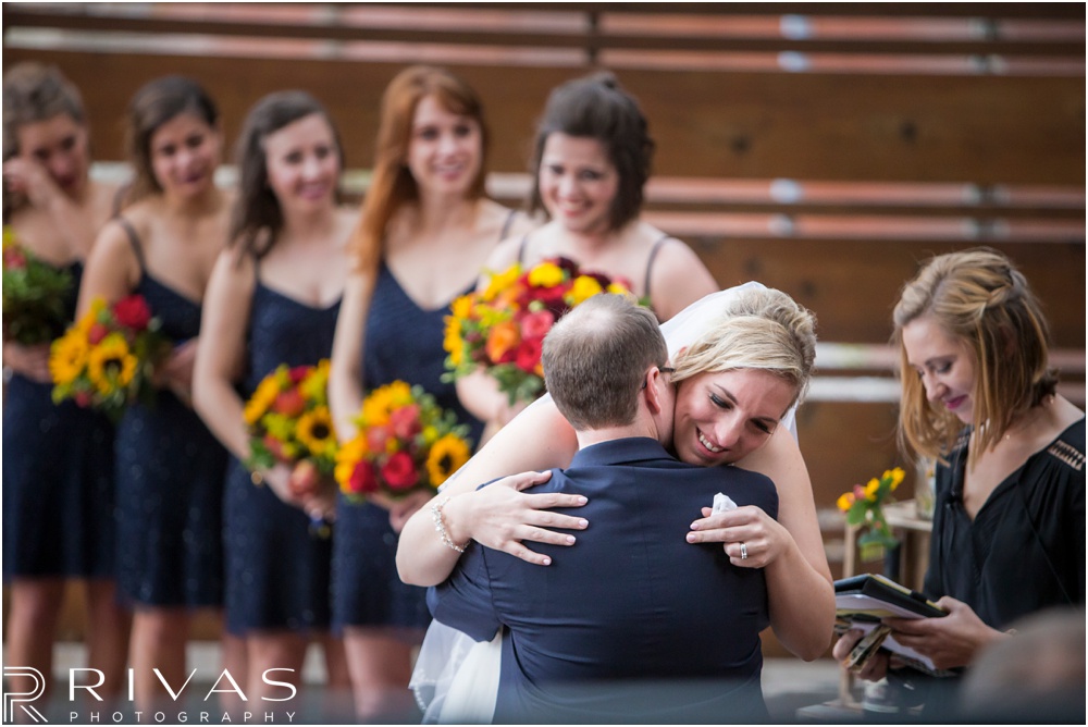 Rustic Outdoor Fall Wedding | A photo of a bride hugging her groom during their wedding ceremony. 