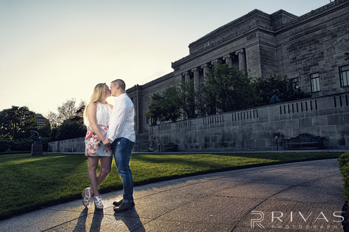 Nelson Engagement Sneak Peek | A picture of a bride and groom holding hands and kissing in front of The Nelson Atkins Museum of Art. 