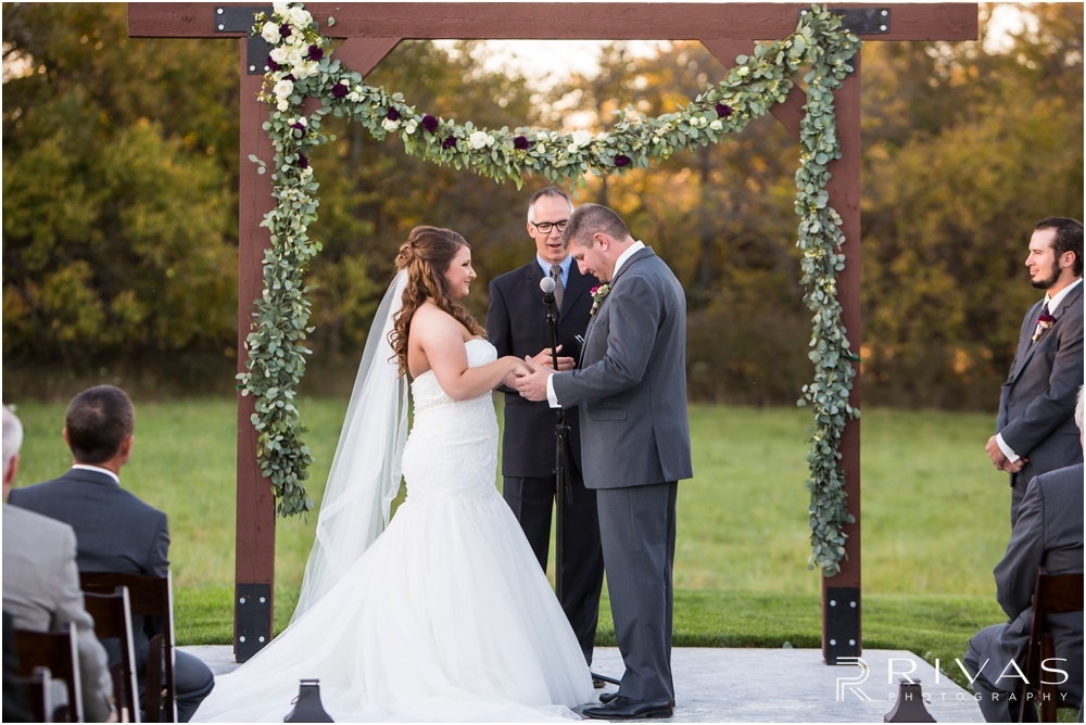 elegant fall wedding buffalo lodge | A bride and groom exchange rings during a sunset wedding ceremony at The Buffalo Lodge
