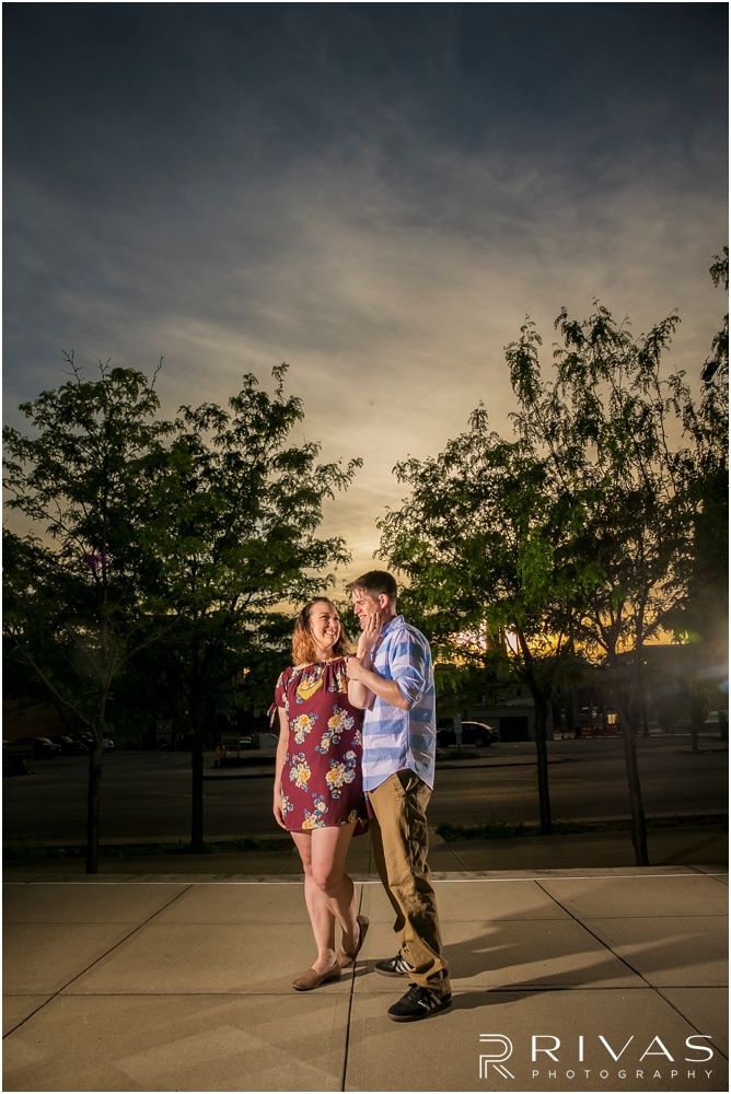 KC Star Engagement Sneak Peek | A picture of an engaged couple standing in front of sunset on the west side of The Kansas City Star Building. 
