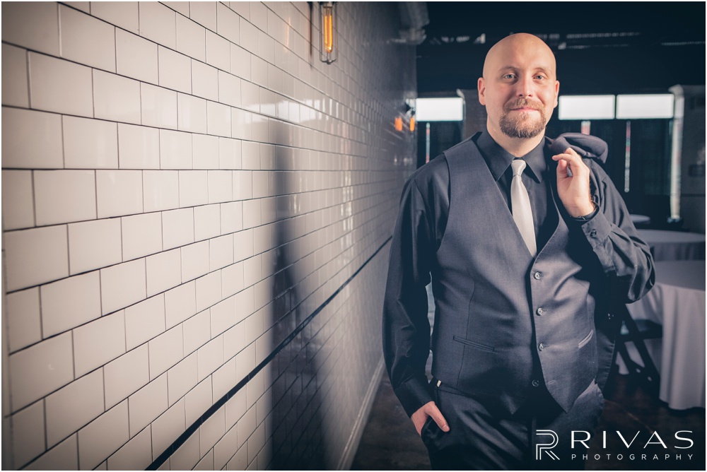Vibrant Spring Wedding at The Guild | Picture of a groom dressed in a black tux standing in front of the white subway tile wall at The Guild KC. 