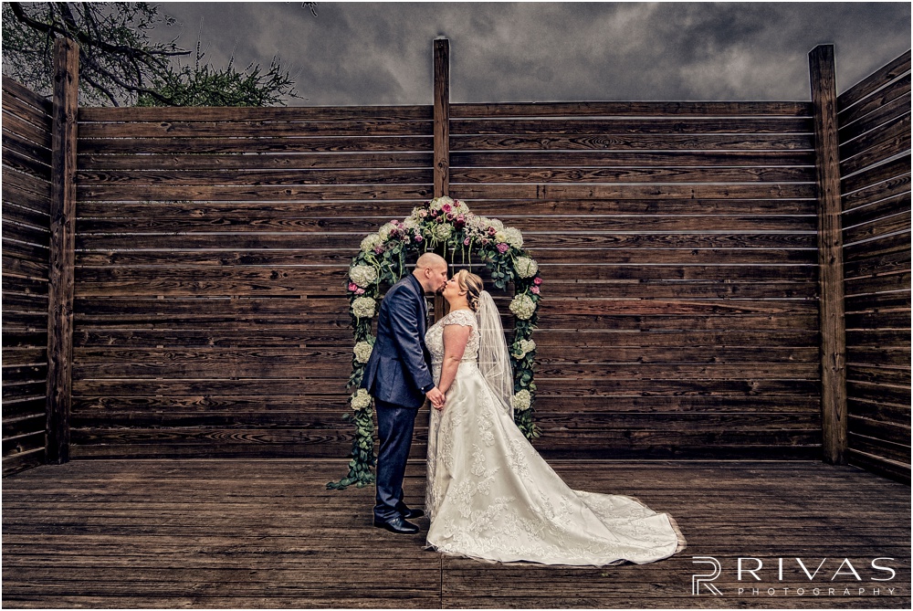 Vibrant Spring Wedding at The Guild | A picture of a bride and groom kissing just after their first look on their wedding day in the courtyard at The Guild KC. 