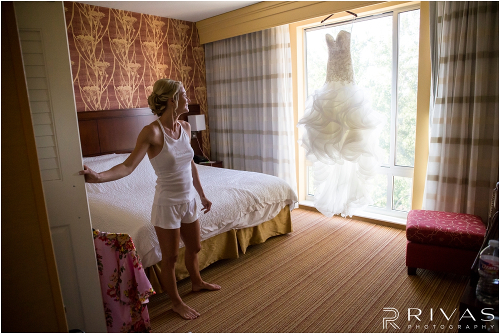 Staley Farms Golf Club Summer Wedding | A picture of a bride looking at her wedding dress hanging in the door of the Courtyard Marriott Kansas City. 