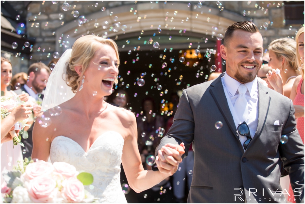 Staley Farms Golf Club Summer Wedding | A candid picture of a bride and groom leaving the church after their wedding ceremony to family and friends blowing bubbles. 