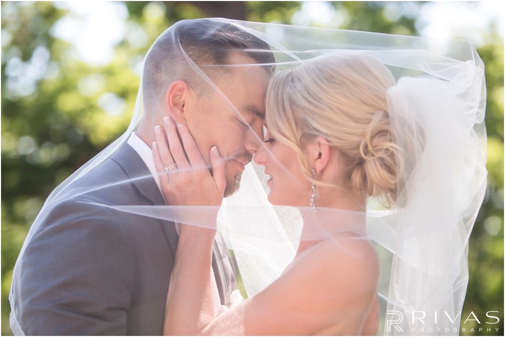 Staley Farms Golf Club Summer Wedding | An intimate portrait of a bride and groom standing underneath the bride's veil after their wedding in Kansas City.  