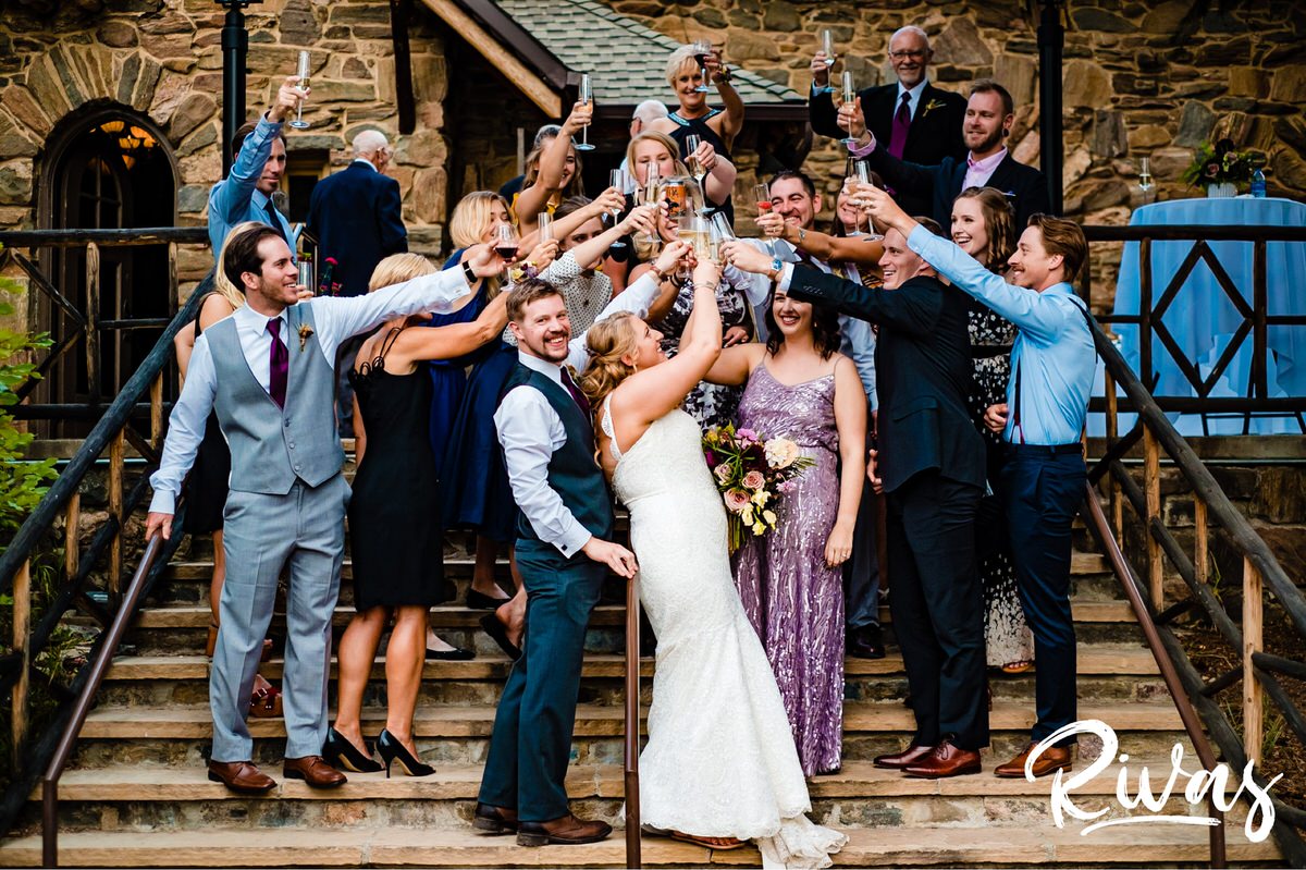 8 Things Your Wedding Photographer Wants you to Know | A group photo of a bride and groom toasting with champagne just after their wedding ceremony celebration. 