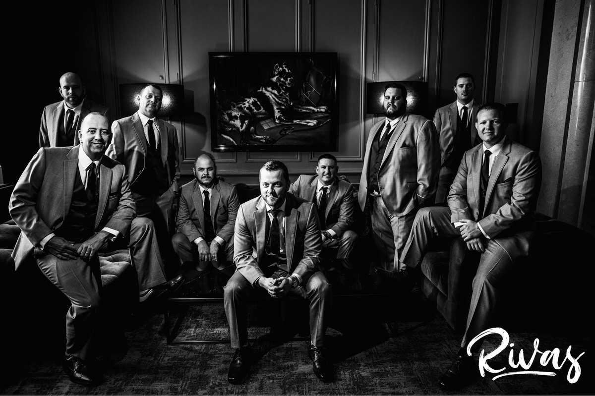 8 Things Your Wedding Photographer Wants you to Know | A formal black and white portrait of a groom and his groomsmen draped across the furniture of The Ambassador Hotel in downtown Kansas City on his wedding day. 