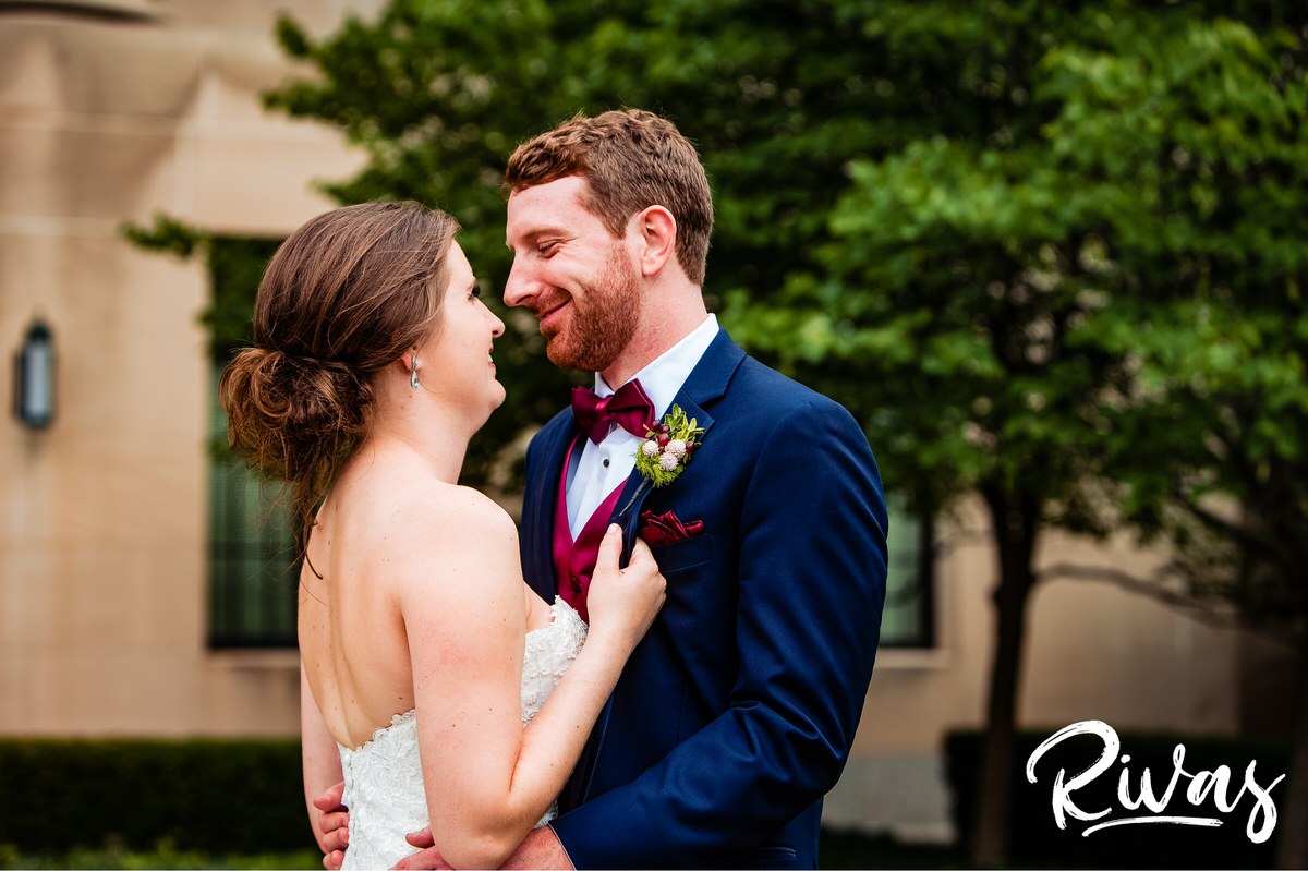 Strawberry Hill Summer Wedding | Rivas Photography | Kansas City Wedding Pictures | A close-up picture of a groom holding his bride around her waist and smiling down at her as she laughs up at him while standing outside the Nelson Atkins Museum of Art in Kansas City. 