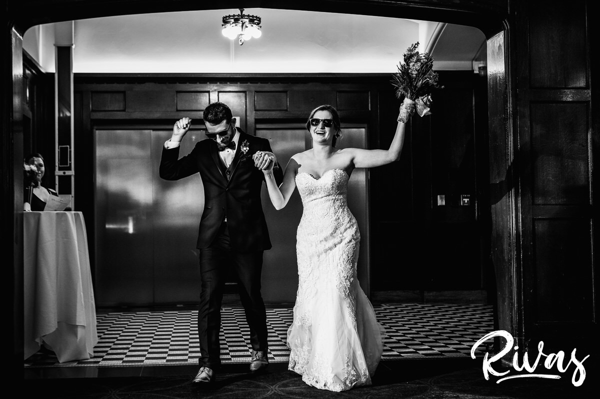 Strawberry Hill Summer Wedding | Rivas Photography | Kansas City Wedding Pictures | A wide, black and white picture of a bride and groom entering their wedding reception held at downtown Kansas City's Brass on Baltimore in the Tudor Room. 