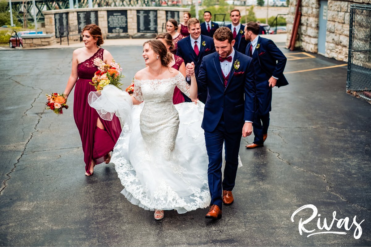 Strawberry Hill Summer Wedding | Rivas Photography | Kansas City Wedding Pictures | A candid image of a bride and groom holding hands and walking together as they happily lead their wedding party into the church. 