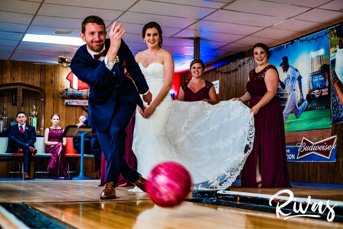 Strawberry Hill Summer Wedding | Rivas Photography | Kansas City Wedding Pictures | A candid picture of a groom tossing a maroon bowling ball as his bride and bridesmaids stand watch in the background. 