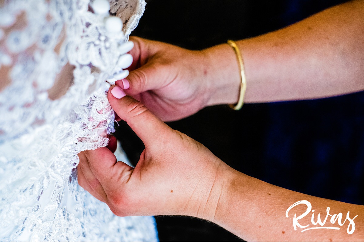 Strawberry Hill Summer Wedding | Rivas Photography | Kansas City Wedding Pictures | A detailed picture of a maid of honor buttoning the back of the bride's wedding gown on the morning of her Kansas City wedding. 