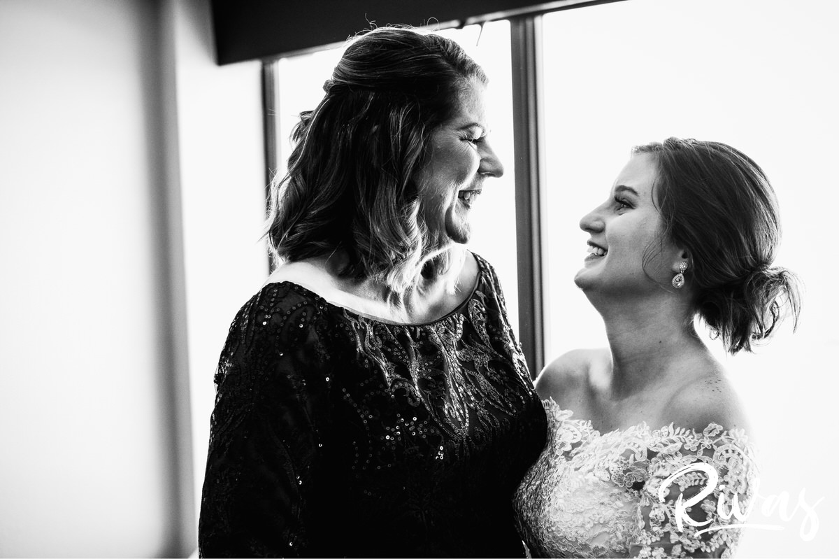 Strawberry Hill Summer Wedding | Rivas Photography | Kansas City Wedding Pictures | A candid black and white picture of a bride and her mother embracing and sharing a laugh togetherjust after the bride has gotten dressed on the morning of her mother's wedding. 