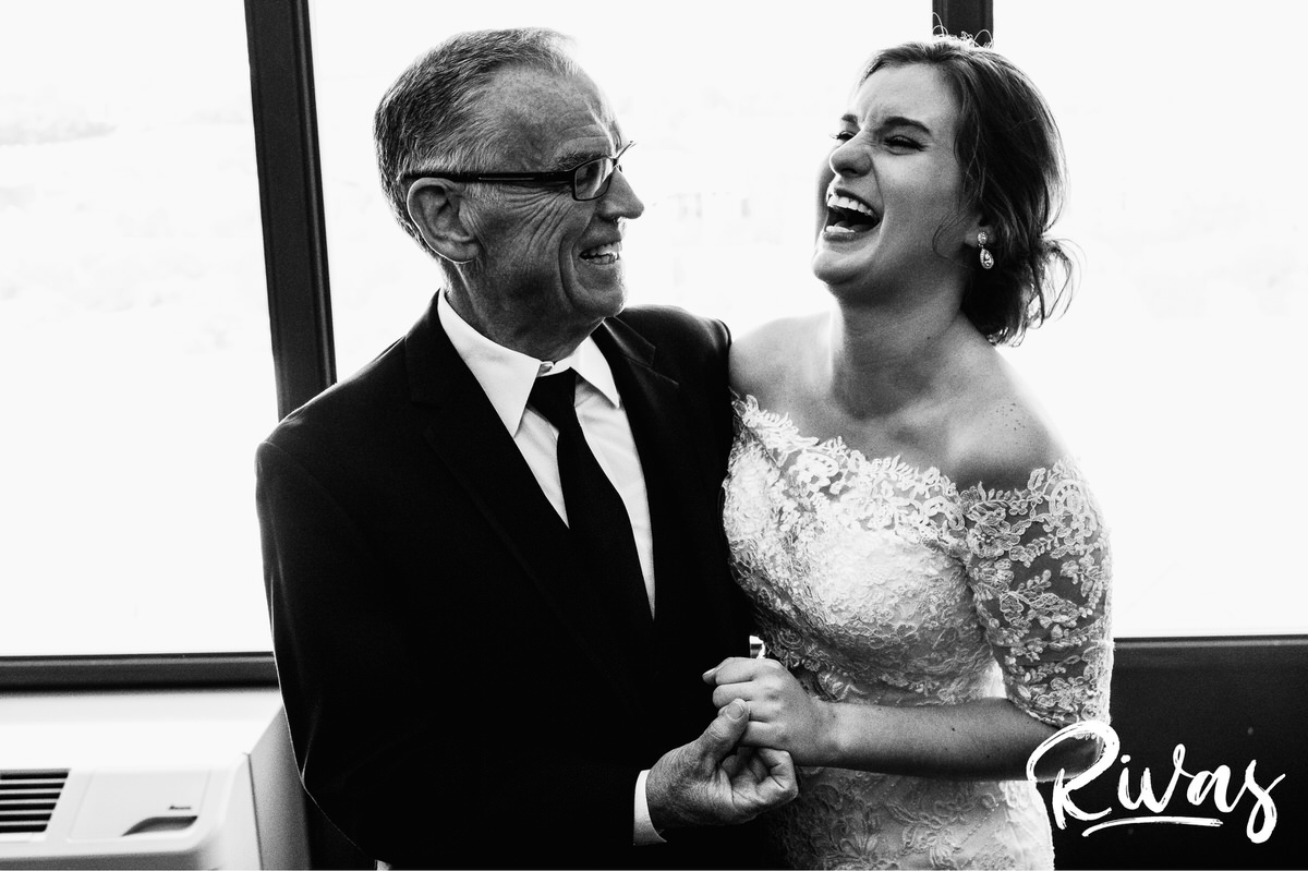 Strawberry Hill Summer Wedding | Rivas Photography | Kansas City Wedding Pictures | A candid black and white photo of a bride and her father sharing an embrace and laughing together on the morning of her wedding day in Kansas City. 