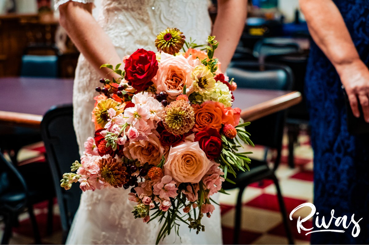Strawberry Hill Summer Wedding | Rivas Photography | Kansas City Wedding Pictures | A close-up photo of a bride holding her bouquet full of red, pink, and orange blooms. 