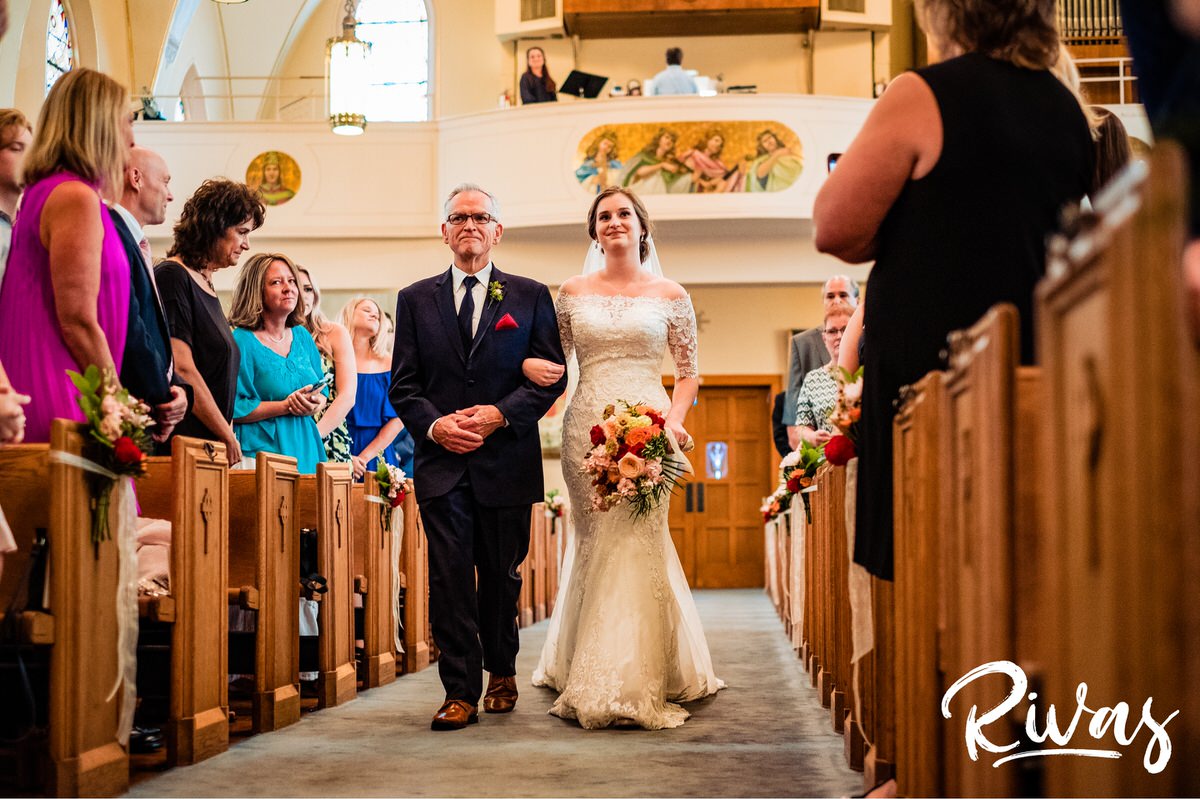 Strawberry Hill Summer Wedding | Rivas Photography | Kansas City Wedding Pictures | A photo taken from the end of the aisle as a bride is escorted down the aisle by her father on the day of her Kansas City wedding. 
