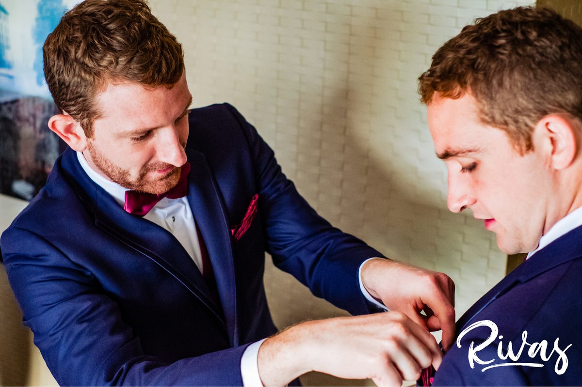Strawberry Hill Summer Wedding | Rivas Photography | Kansas City Wedding Pictures | A picture of a groom tucking a pocket square into the pocket of his brother's tuxedo jacket in Kansas City on the morning of his wedding. 