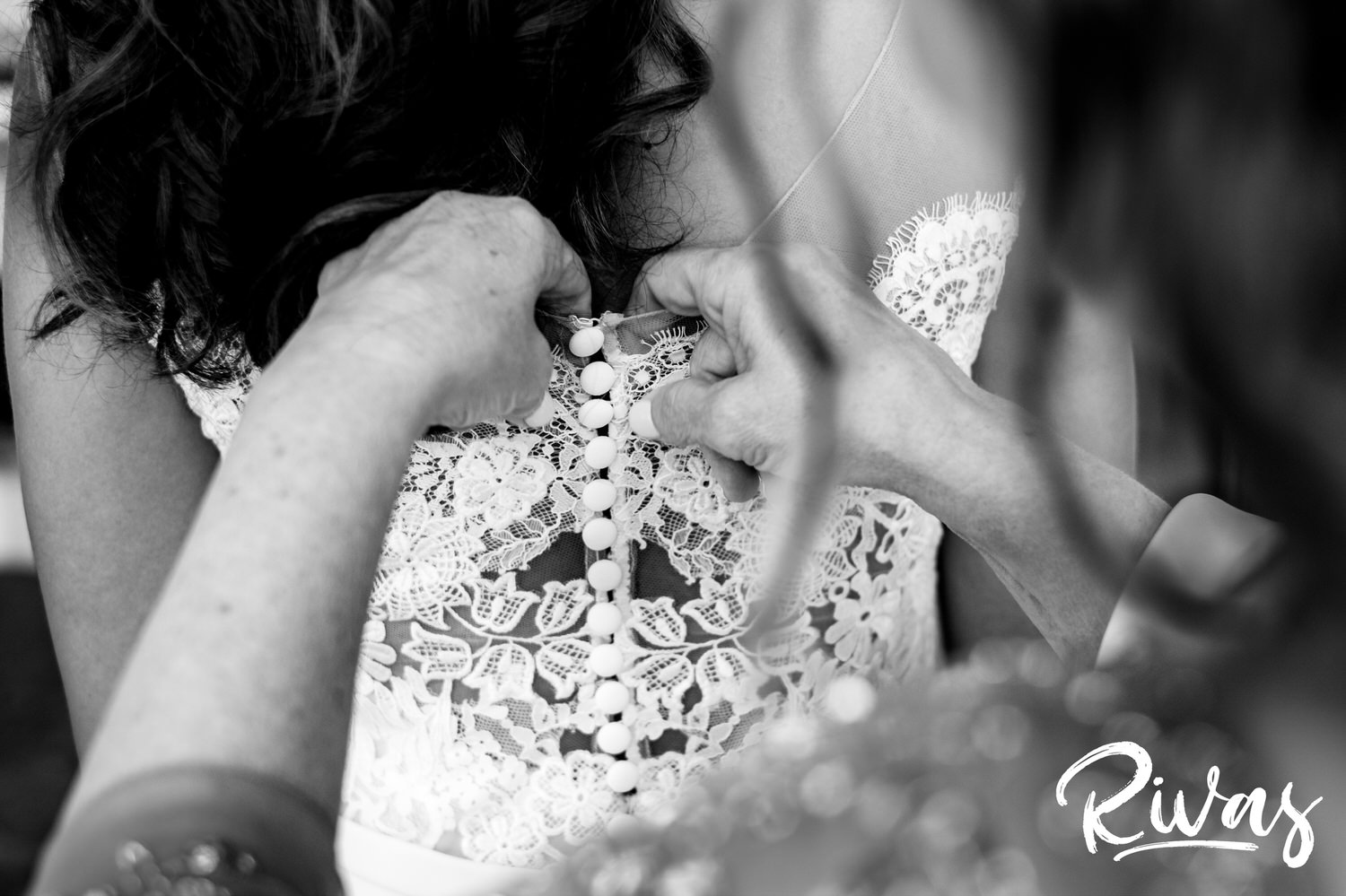 Saddlerock Ranch Summer Wedding | Destination Wedding Photographers | Rivas | A detailed black and white photo of a bride's mom buttoning the final buttons on her daughter's wedding gown on the morning of her wedding at Saddlerock Ranch in Malibu. 