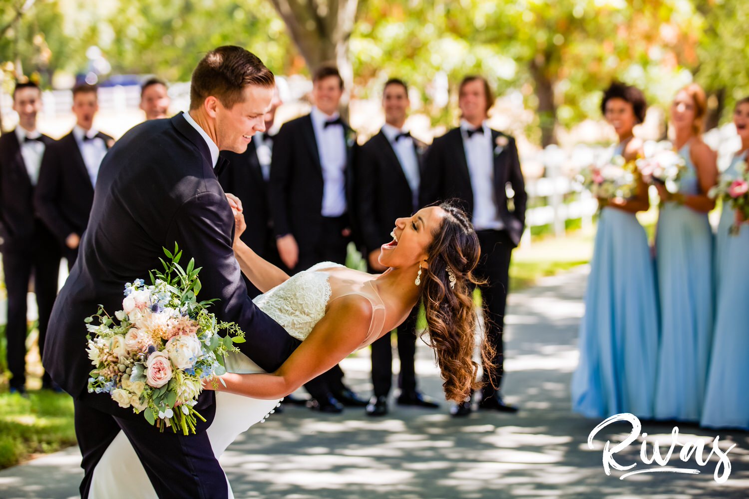 Saddlerock Ranch Summer Wedding | Destination Wedding Photographers | Rivas | A candid image of a groom dipping his bride in front of their bridal party on their wedding day at Saddlerock Ranch in Malibu. 
