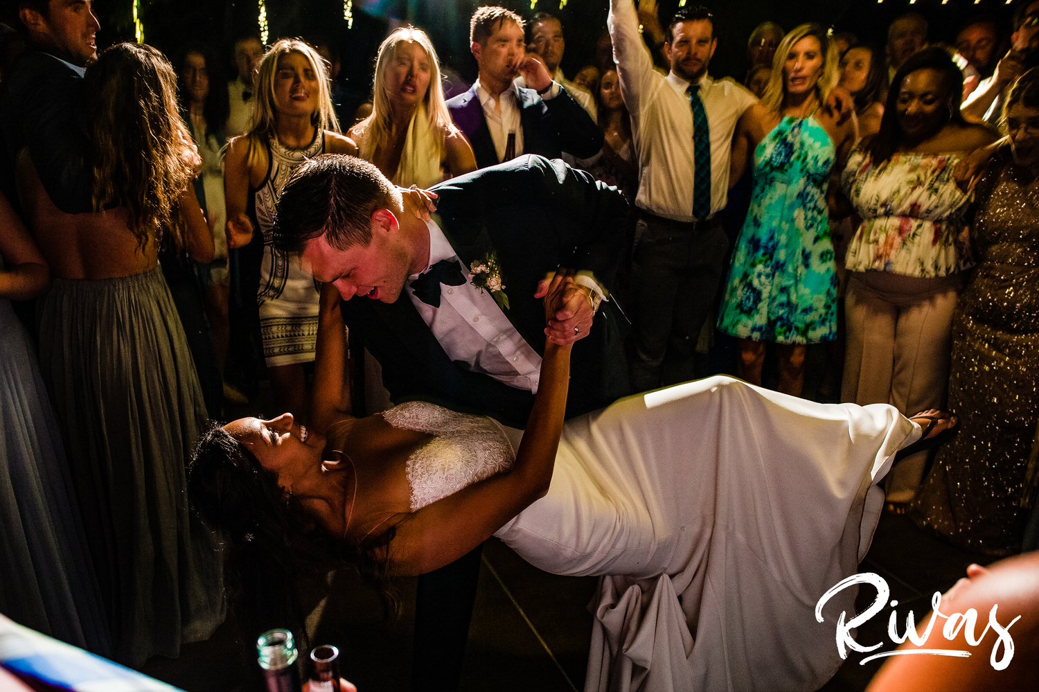 Saddlerock Ranch Summer Wedding | Destination Wedding Photographers | Rivas | A candid image of a groom dipping his bride during their last dance while friends and family cheer them on during their wedding reception at Saddlerock Ranch in Malibu, CA. 