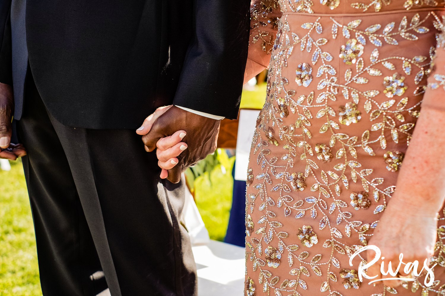 Saddlerock Ranch Summer Wedding | Destination Wedding Photographers | Rivas | A close-up photo of a bride's mom and dad holding hands during their daughter's wedding ceremony. 