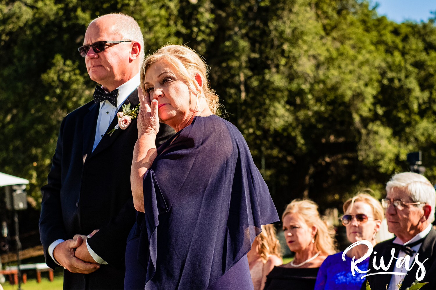 Saddlerock Ranch Summer Wedding | Destination Wedding Photographers | Rivas | A candid image of the groom's mother and father wiping tears from their eyes during their son's wedding ceremony. 