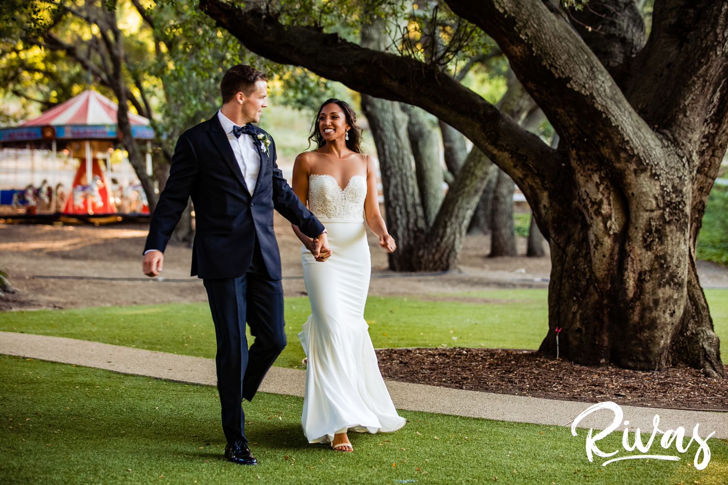 Saddlerock Ranch Summer Wedding | Destination Wedding Photographers | Rivas | A photo of a bride and groom walking into their Saddlerock Ranch wedding reception holding hands and laughing. 