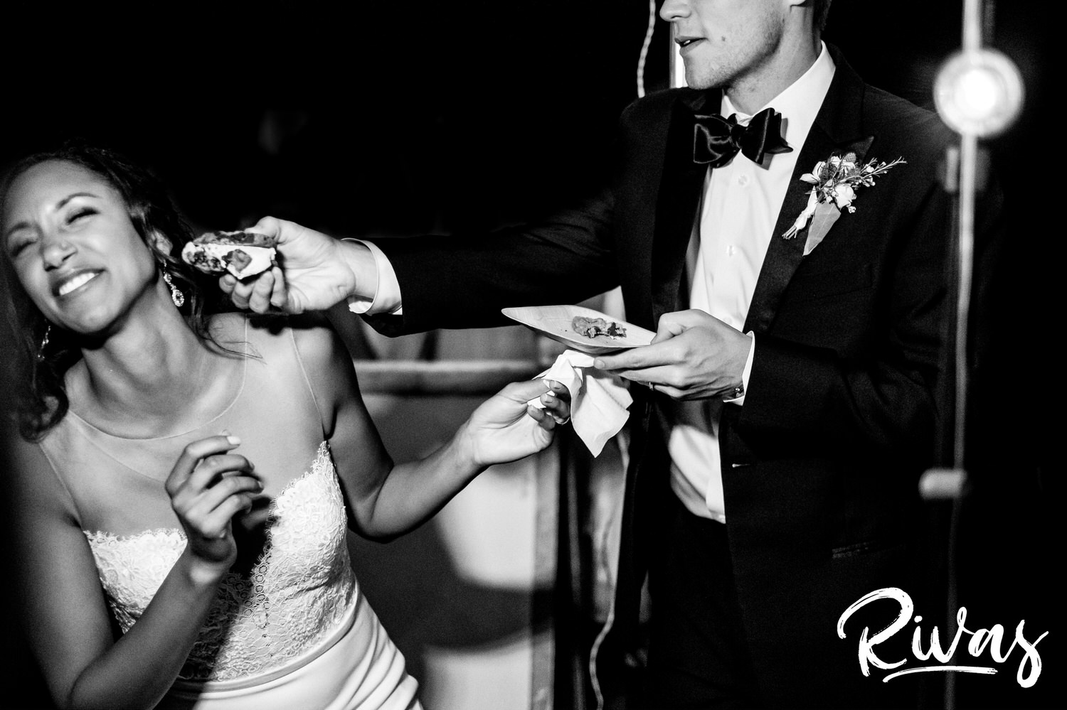 Saddlerock Ranch Summer Wedding | Destination Wedding Photographers | Rivas | A black and white candid picture of a groom shoving an ice cream sandwich into his bride's face as she ducks to try to avoid it during their Saddlerock Ranch wedding reception. 