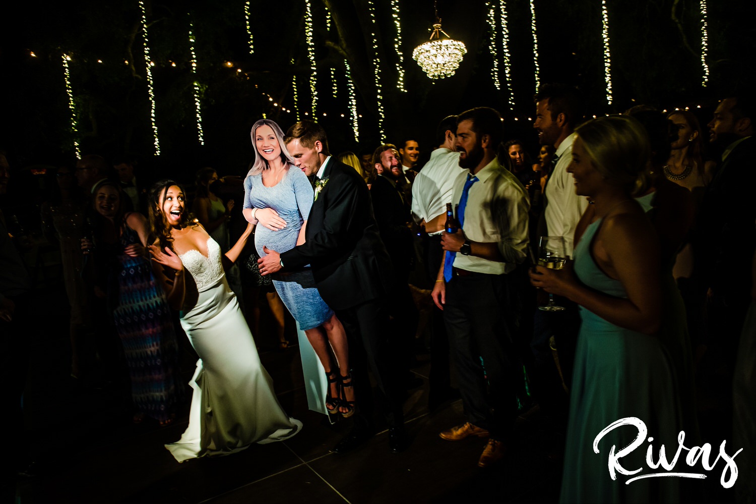 Saddlerock Ranch Summer Wedding | Destination Wedding Photographers | Rivas | A photo of a bride and groom dancing with a life size cutout of a pregnant bridesmaid on their dance floor at their Saddlerock Ranch wedding reception. 