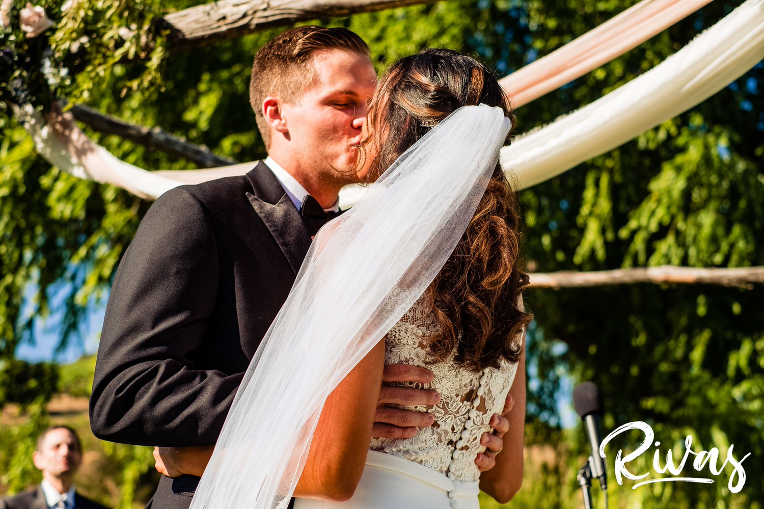 Saddlerock Ranch Summer Wedding | Destination Wedding Photographers | Rivas | A close-up picture of the bride and groom sharing their first kiss as her veil blows in the breeze. 
