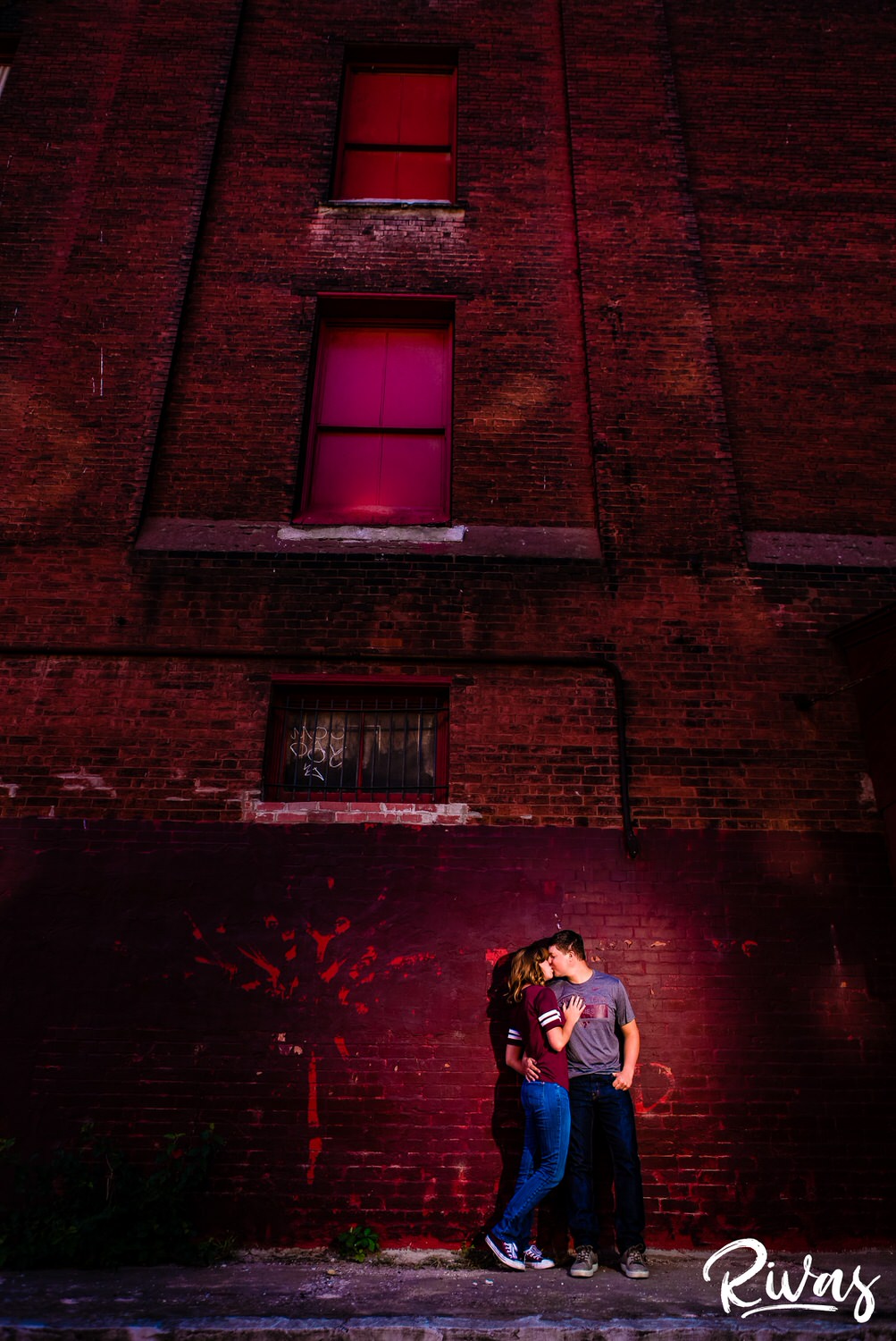 Kansas City Engagement Pictures | West Bottoms Engagement Session | A dramatic picture of an engaged couple standing outside a brick building in Kansas City's West Bottoms Neighborhood wearing Virginia Tech clothes. 