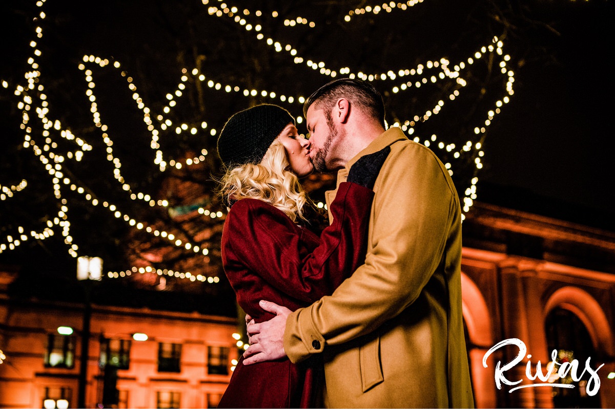 KC Winter Lights Engagement Pictures | Kansas City engagement Pictures | Rivas | A picture of an engaged couple walking arm in arm through a cluster of trees lit with white Christmas lights outside Kansas City's Union Station during their engagement Session. 