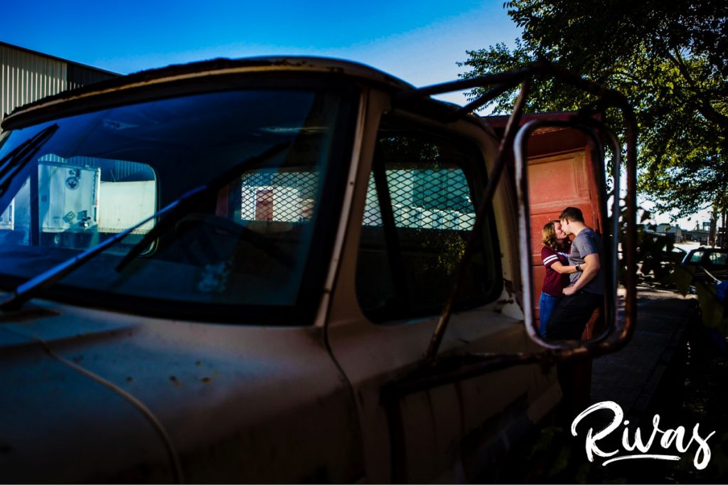 KC West Bottoms Engagement Pictures | A picture of an engaged couple embracing and laughing together in the reflection of a truck's mirror. 