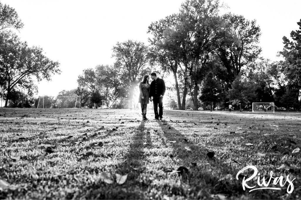 West Bottoms Engagement Pictures | A black and white picture of an engaged couple walking through a park at sunset. 