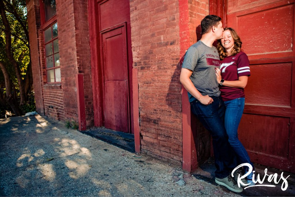 West Bottoms Engagement Pictures | a picture of a couple dressed in Virginia Tech gear holding hands and laughing together in Kansas City's West Bottoms neighborhood. 