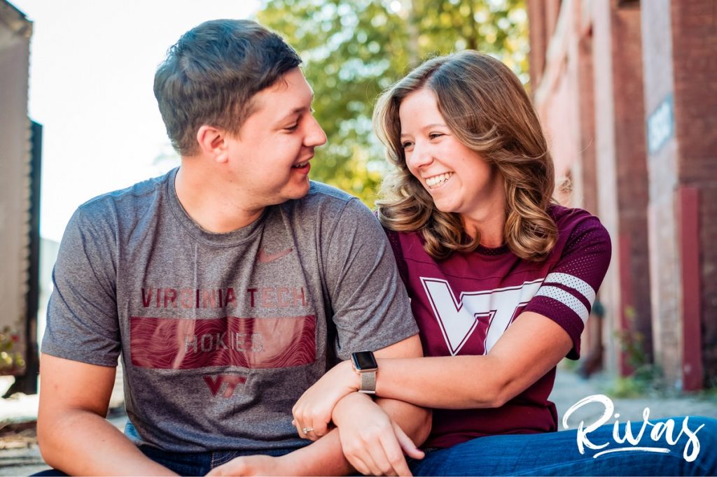 West Bottoms Engagement Pictures | A casual picture of an engaged couple in Virginia Tech gear sitting on stairs, laughing and embracing. 