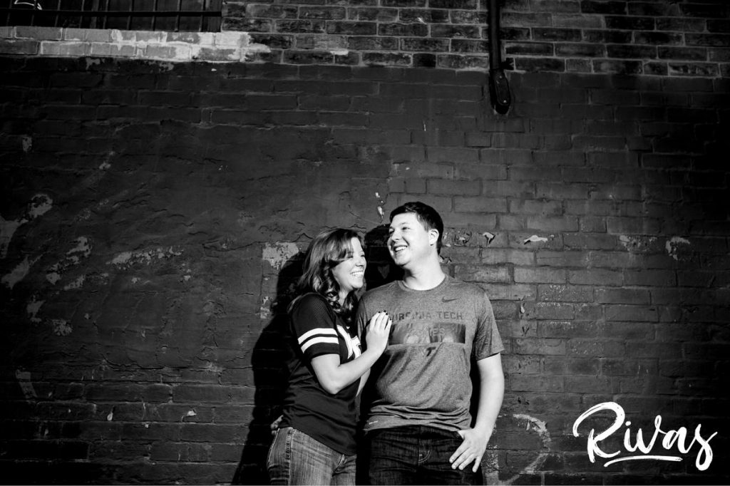 West Bottoms Engagement Pictures | A black and white picture of an engaged couple standing up against a brick wall. 