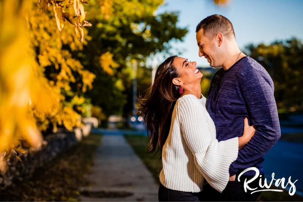 Colorful Nelson Engagement Session | A candid picture of an engaged couple embracing and laughing together during their casual fall engagement session on the East side of the Nelson Atkins Museum of Art in Kansas City. 