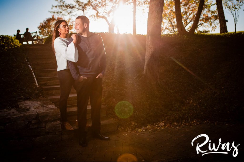 Colorful Nelson Engagement Session | A colorful, candid engagement picture of a couple standing on a set of stars as golden rays of light shine through tree branches at The Nelson Atkins Museum of Art. 