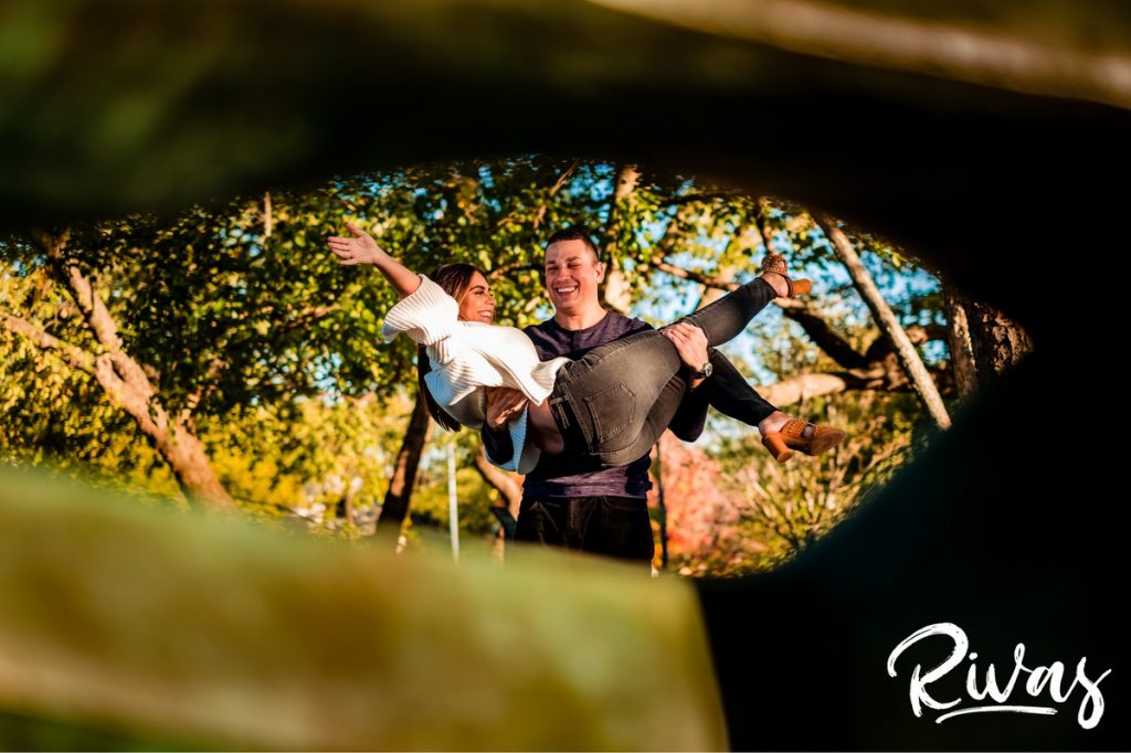 Colorful Nelson Engagement Session | A picture of a groom holding his bride and swinging her through the air during their engagement session at The Nelson Atkins Museum of Art in Kansas City. 