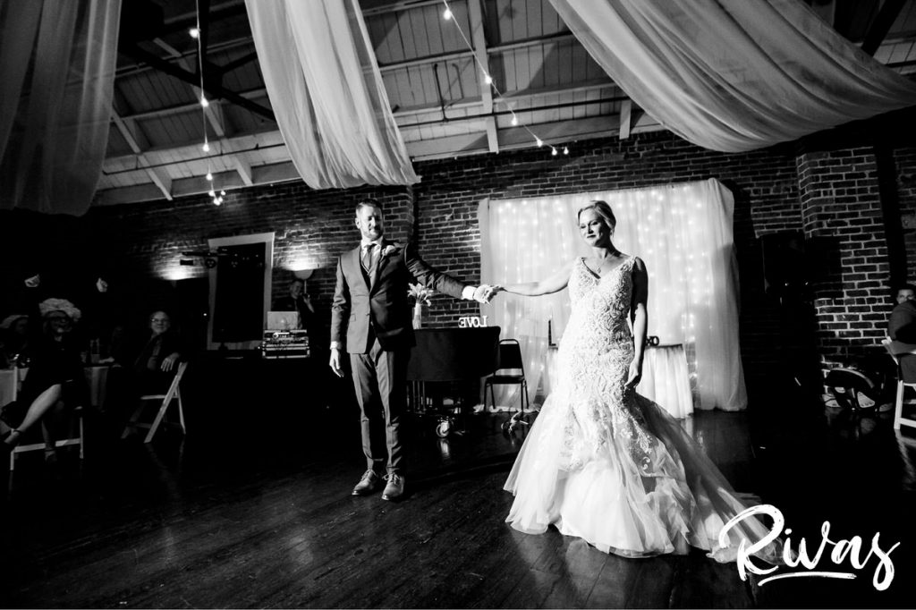 Art Deco Inspired Wedding in Kansas City- A candid picture of a bride and groom walking hand in hand across the dance floor during their wedding reception at Californos. 