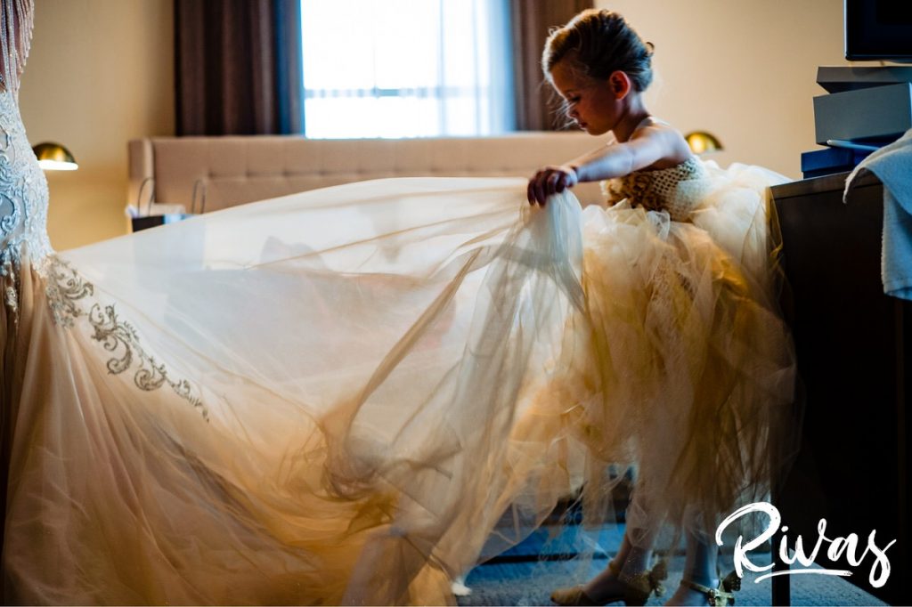 Art Deco Inspired Wedding in Kansas City | A candid picture of a young flower girl fluffing a bride's train of her wedding gown. 